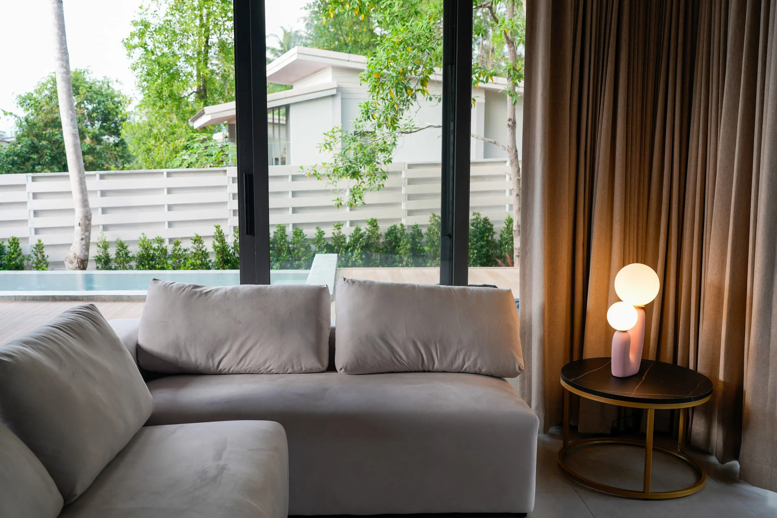 Villa II — velvet sofa by the window with pool and terrace view