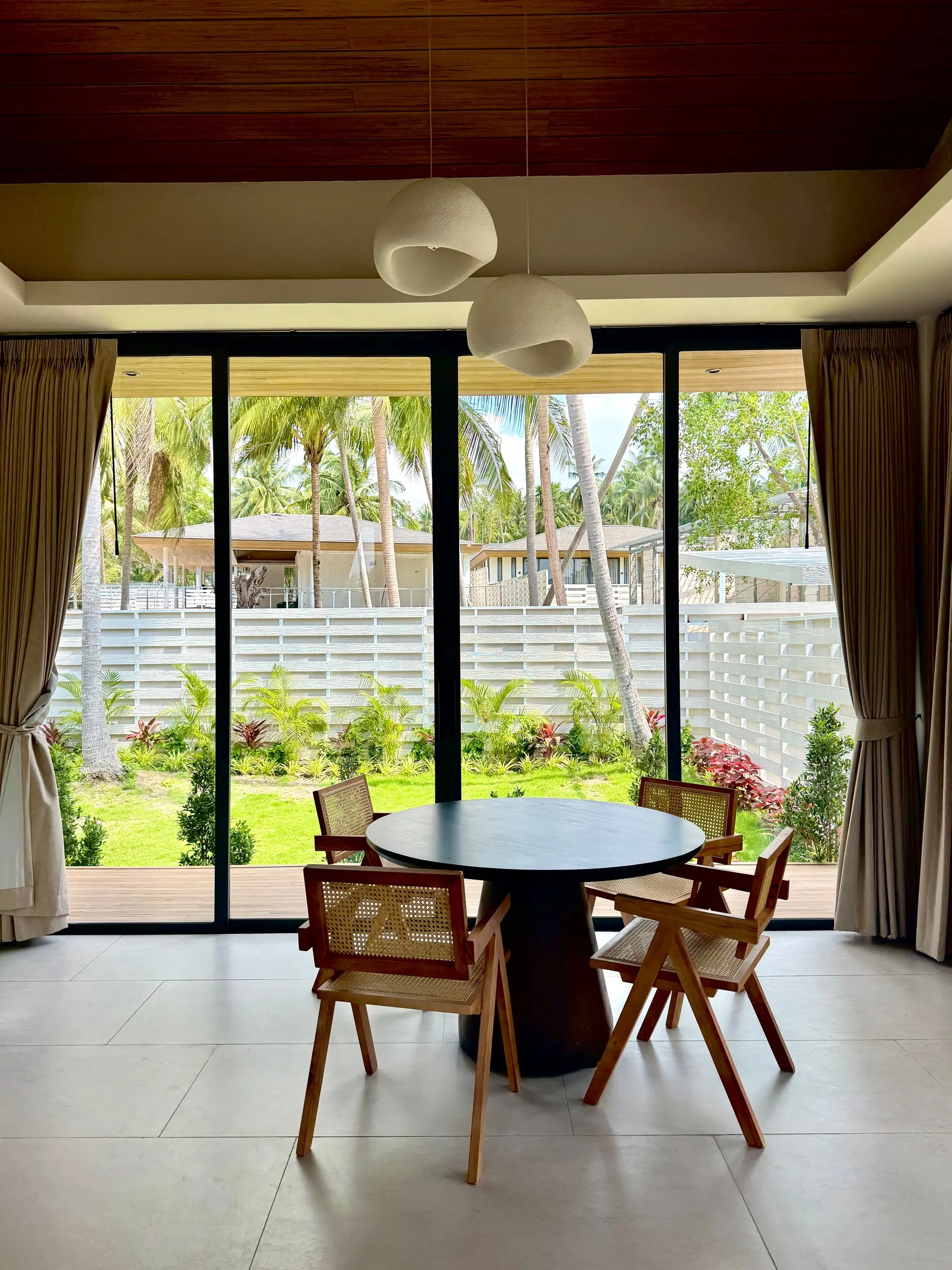 Villa I — dining nook by floor-to-ceiling windows onto the garden