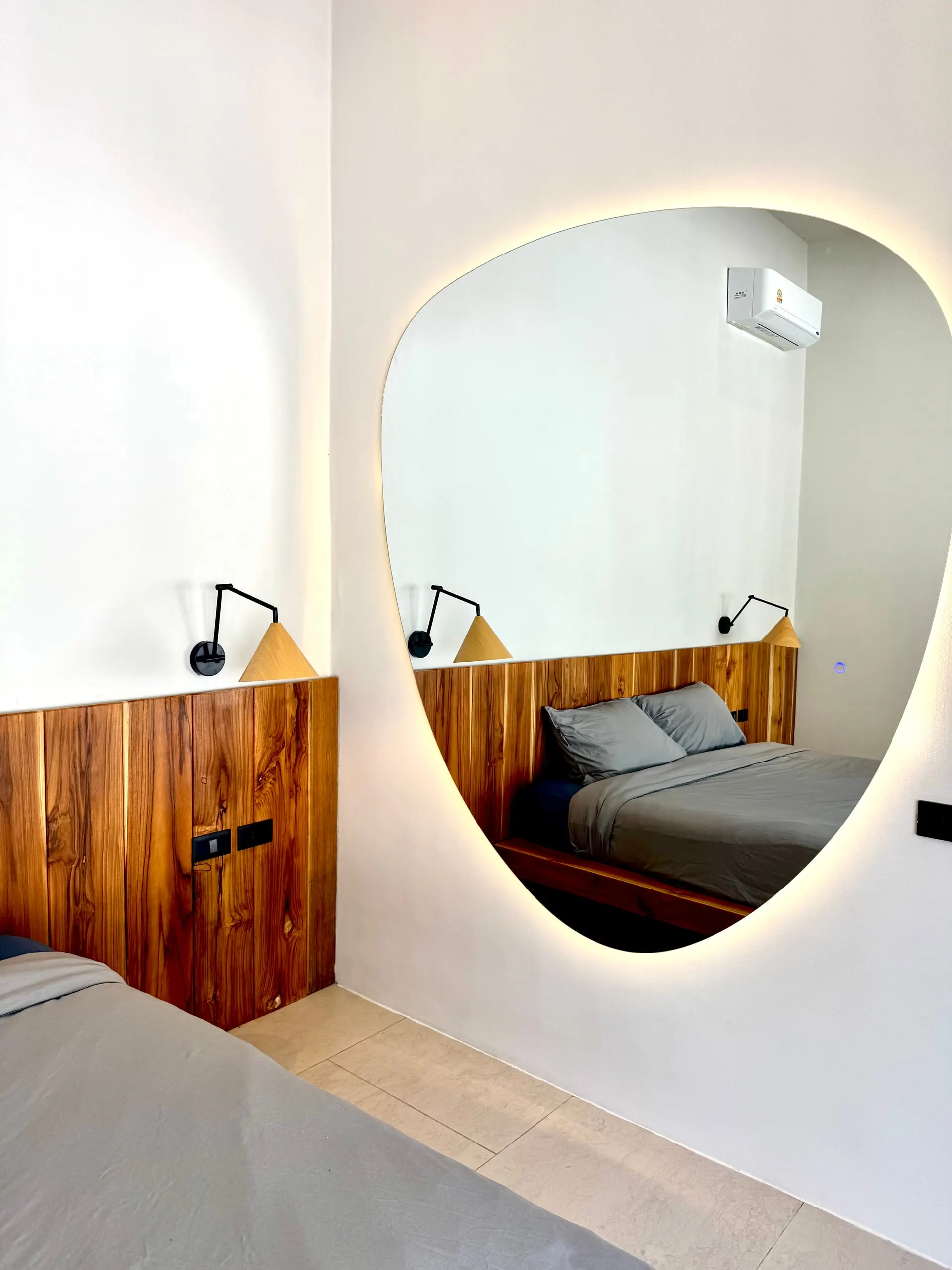 Villa II — bedroom two, backlit mirror and teak panel wall