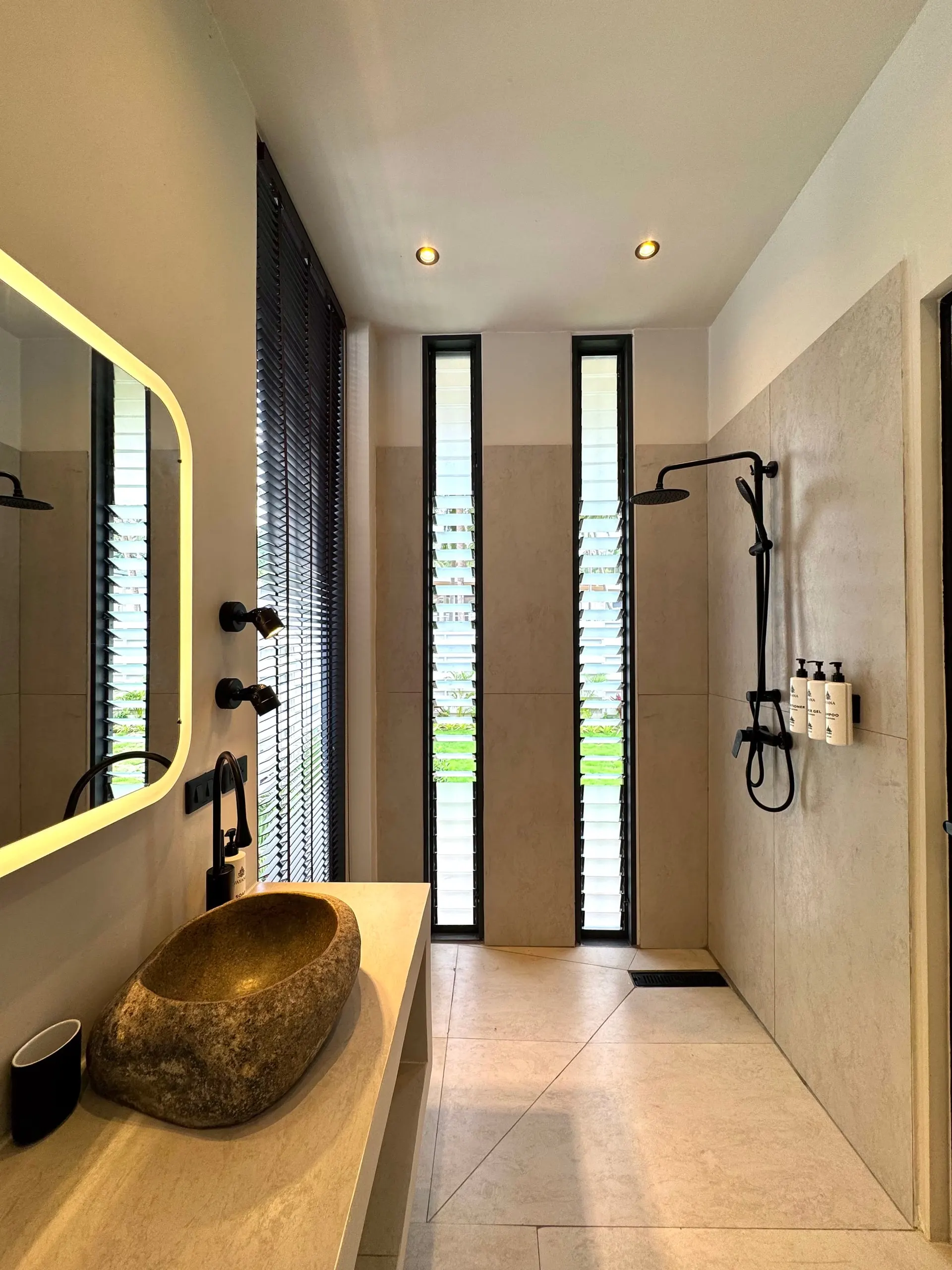 Villa I — bathroom one with a stone-boulder sink and black rain shower