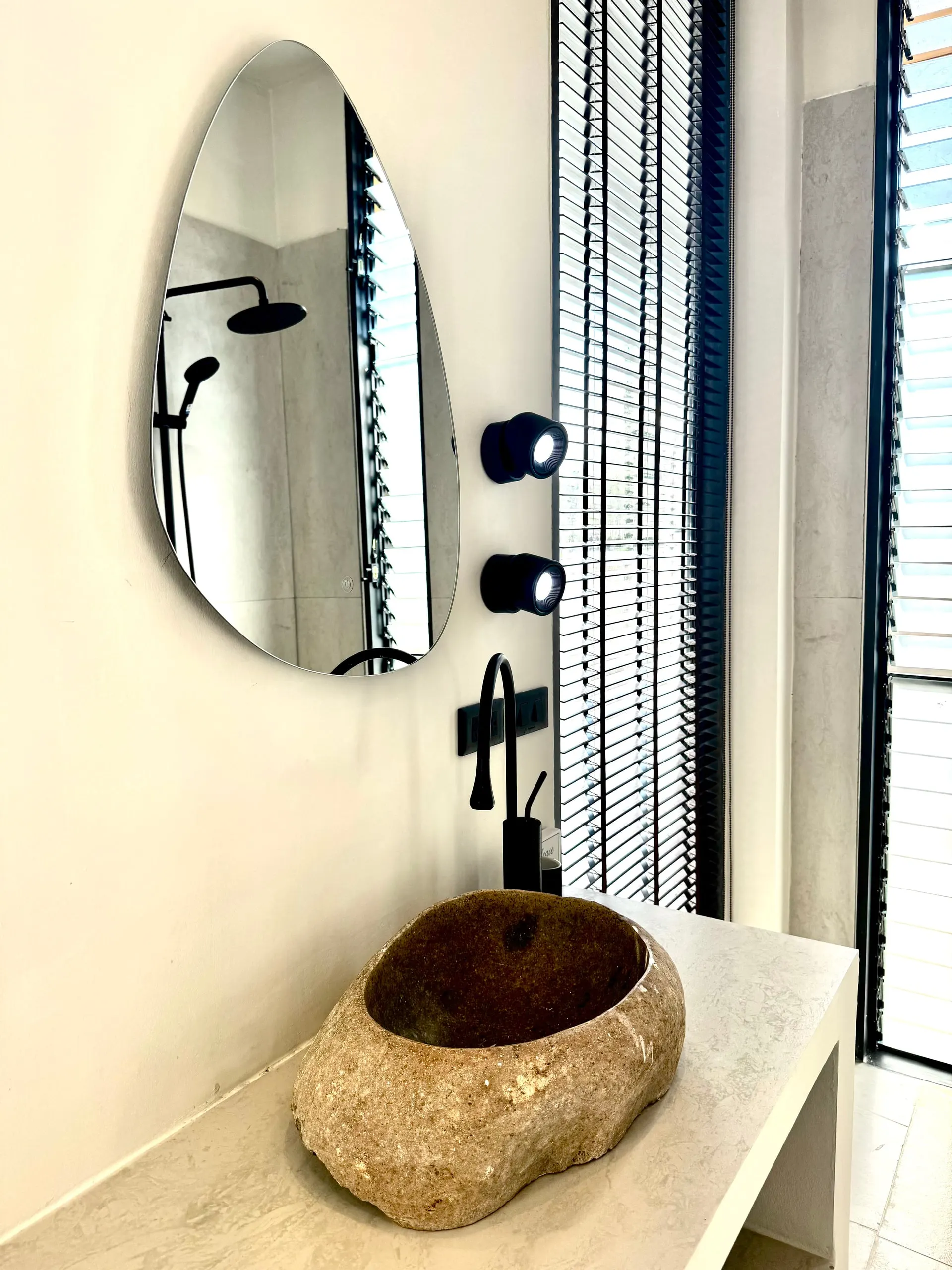 Villa II — teardrop mirror reflecting the black tropical shower
