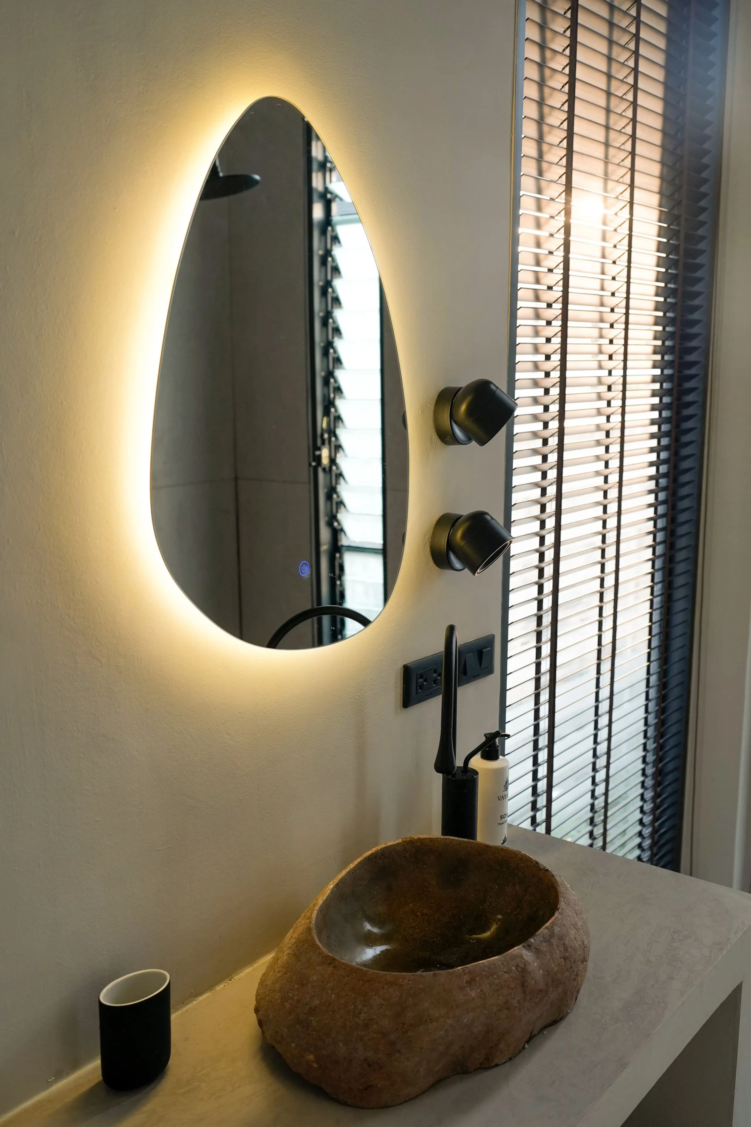 Villa II — bathroom one, natural stone basin under a teardrop mirror
