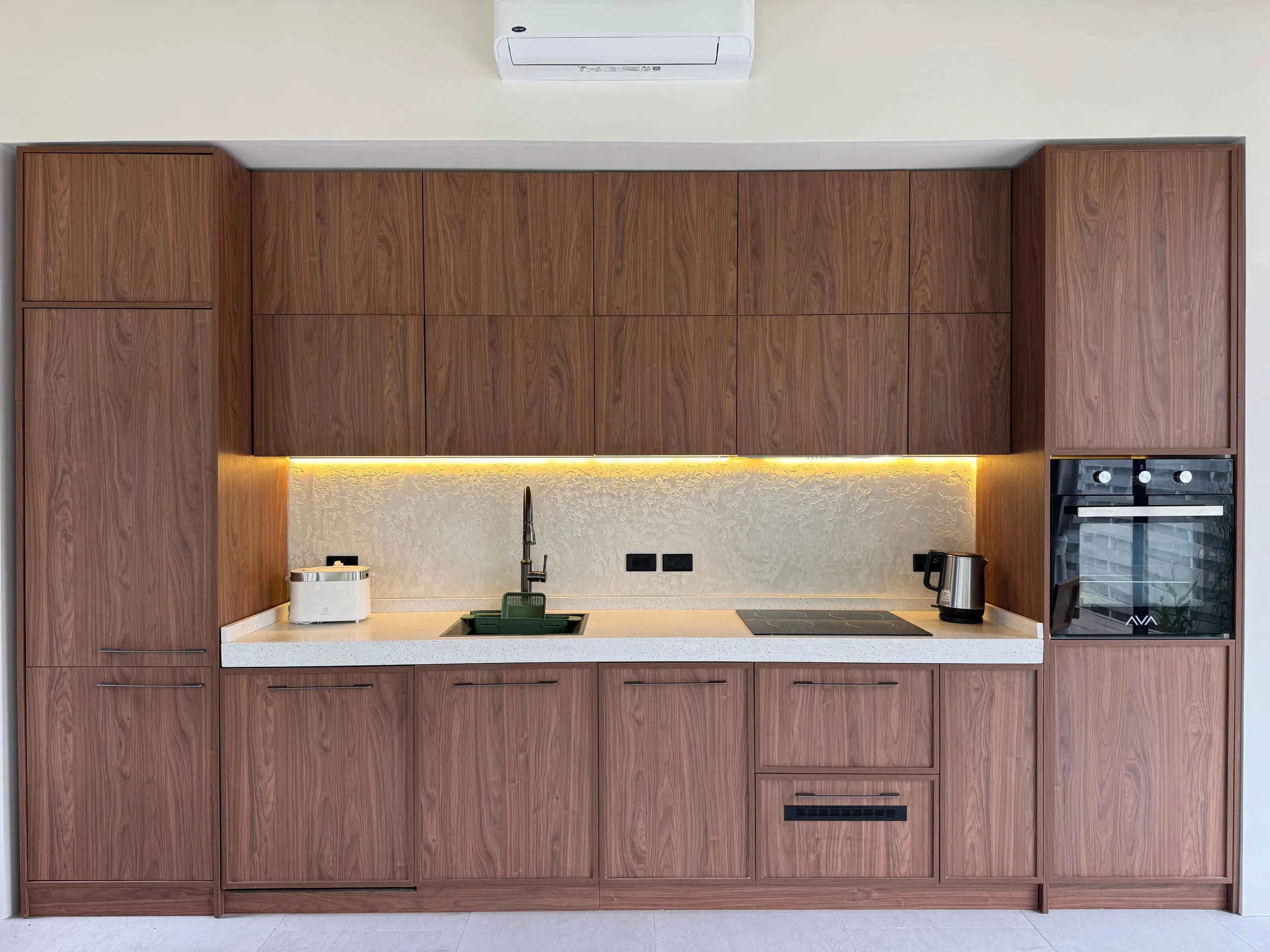 Villa I — full-wall walnut kitchen with hob, oven and hidden lighting