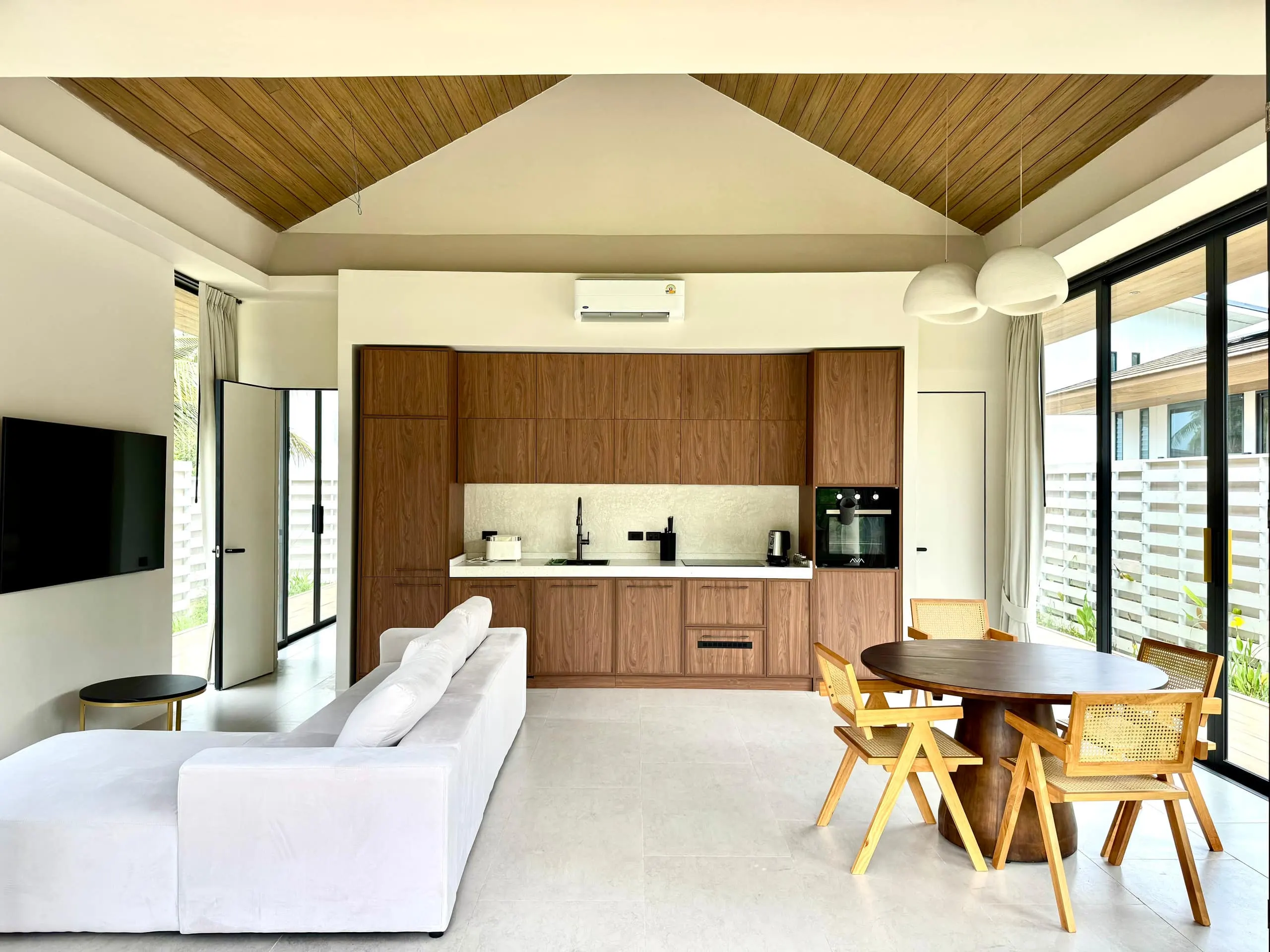 Villa II — open living-kitchen-dining space under the slatted gable ceiling